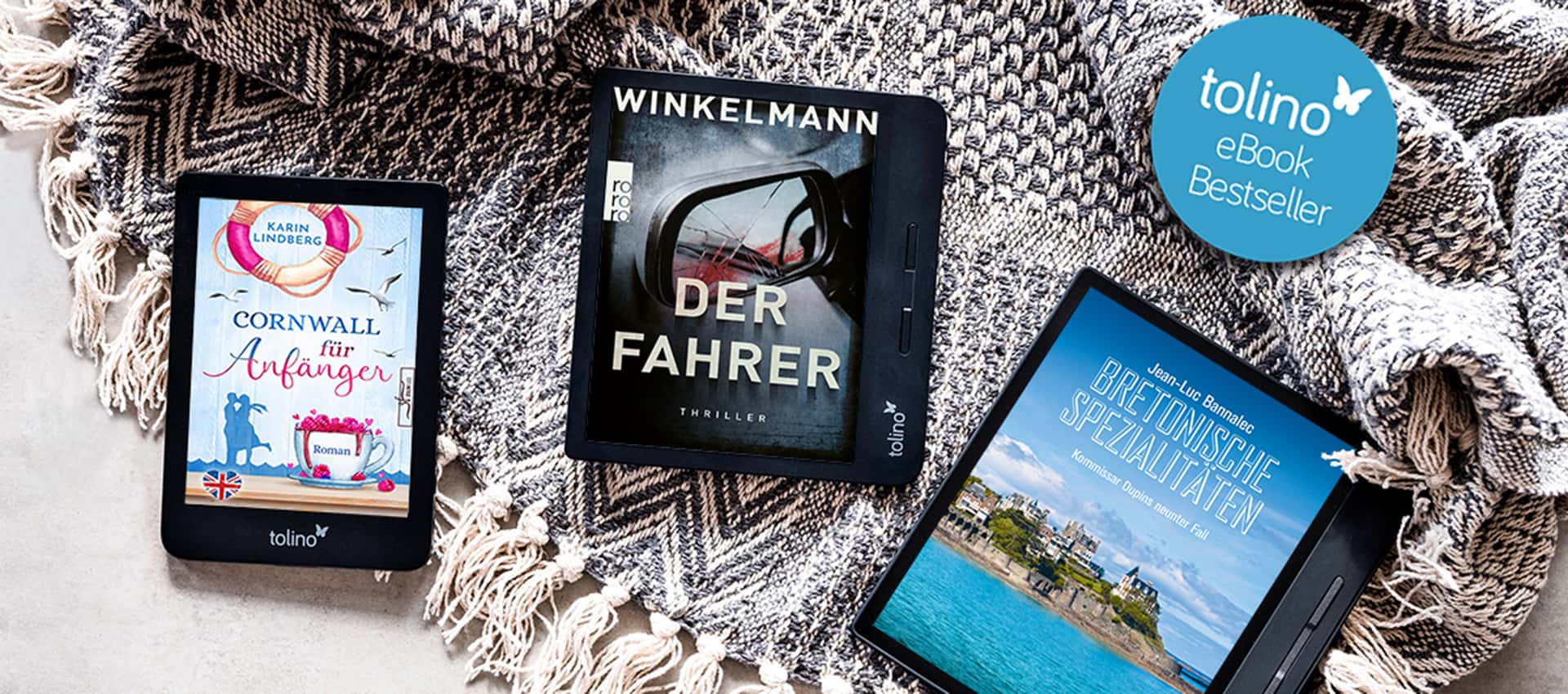 Drei tolino-eReader liegen auf einem Tisch und zeigen die tolino-Bestseller.